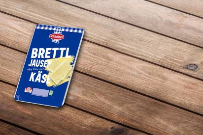 Der Schärdinger Brettljause-Käse in Scheiben auf einem Holzuntergrund.