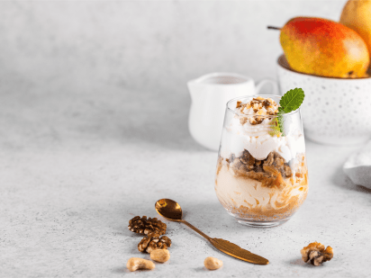 Birnen-Haselnuss-Dessert mit Karamell im Glas mit CremiG Vanille auf einem Tisch mit Birnen und Nüssen
