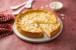 Mandel Tarte mit Schärdinger Cremig auf einem Teller auf einem roten Tischtuch
